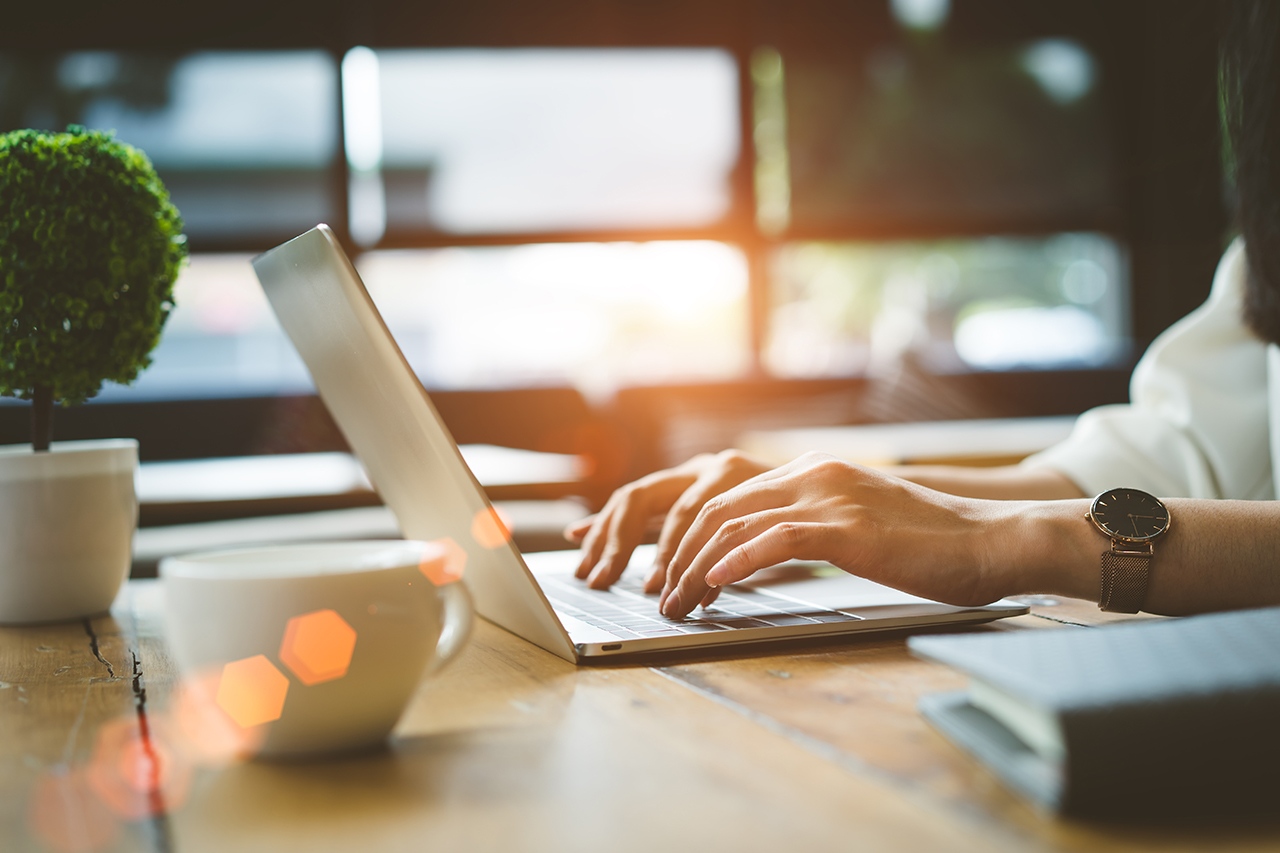 Closeup-hands-of-Freelancer-woman-working-using-digital-laptop-computer-and-drink-coffee-breakfast-on-workplace-table-at-cafe-shop-in-the-morning